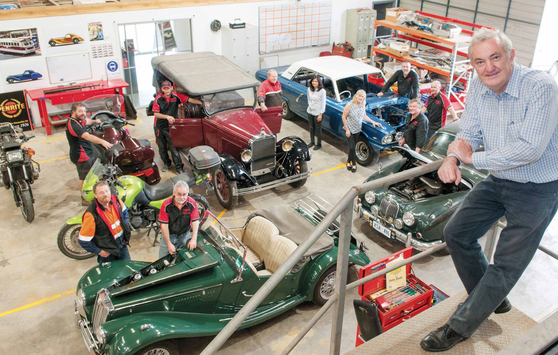 Peter Roberts with his team at Finch Restorations and a selection of vehicles they have worked on. Photo by Phil Martin